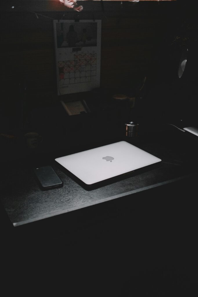 A dark, minimalist workspace featuring a laptop and smartphone on a desk.